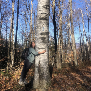 A college student in the forest hugging a tree